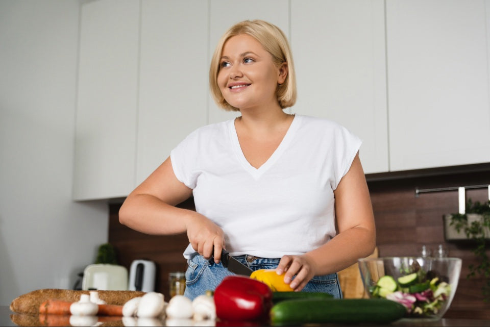 Person preparing fresh vegetables in a kitchen, representing balanced diet and nutritional support.