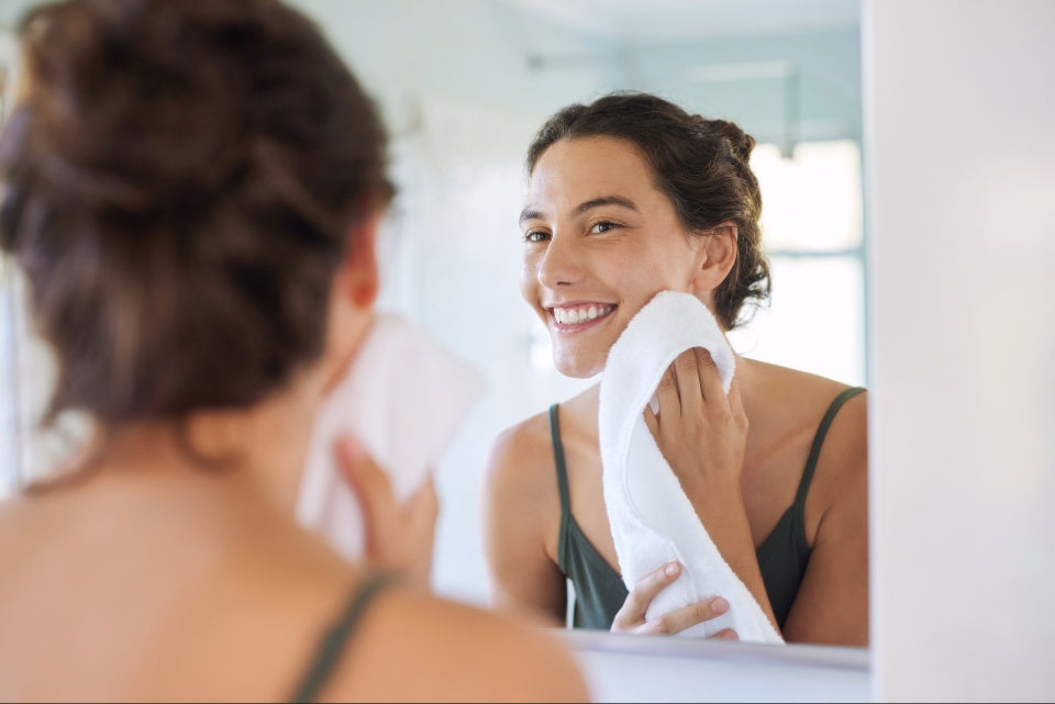 Person in front of mirror wiping face with towel
