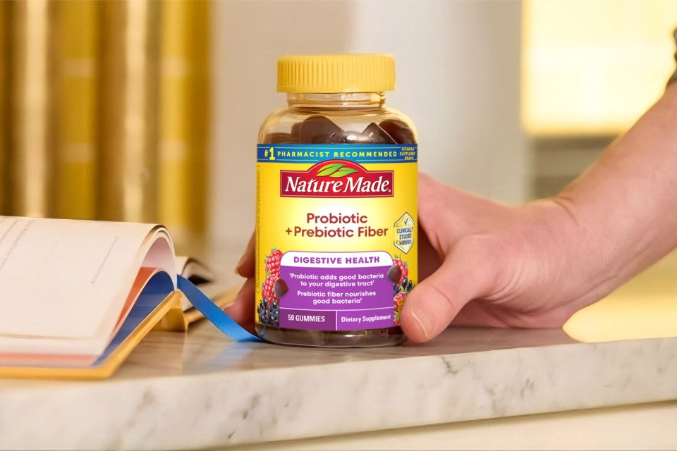 Nature Made Probiotic + Prebiotic Fiber supplement bottle on a counter with a hand holding it.