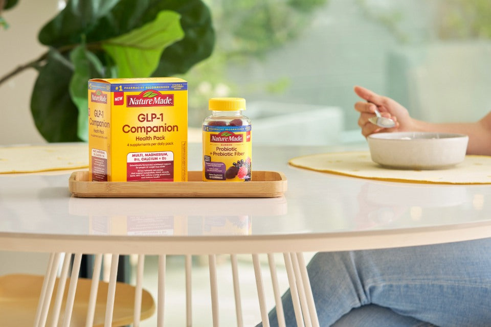 Nature Made GLP-1 Companion Health Pack and Prebiotic Fiber supplement on a tray on a dining table.