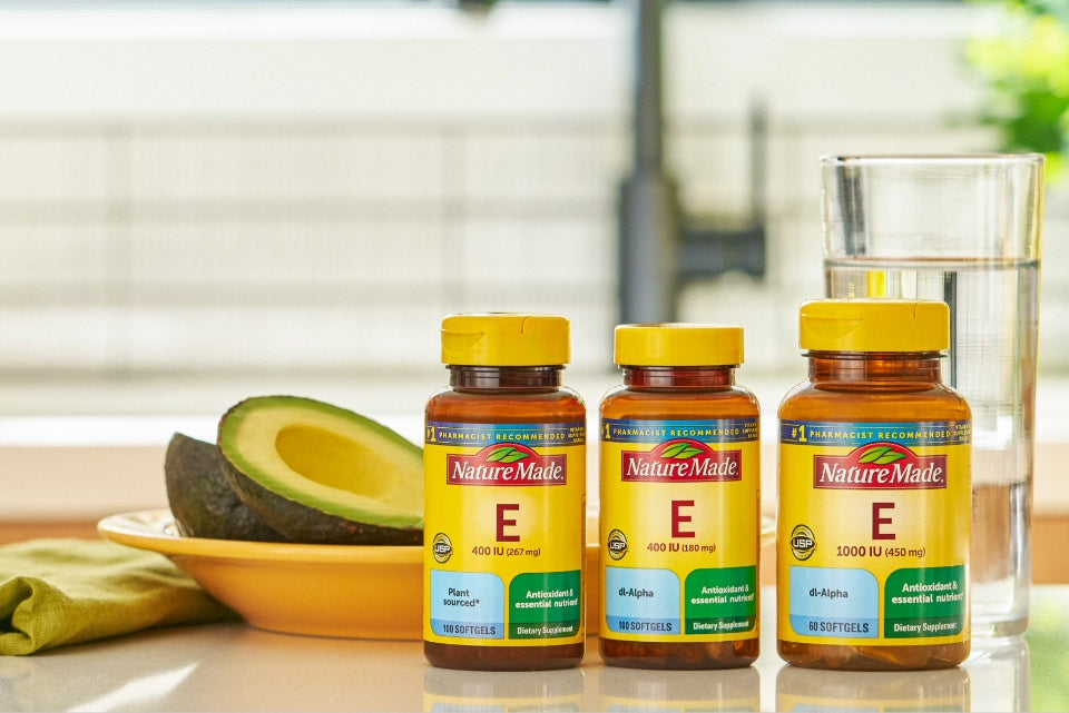 Nature Made Vitamin E supplements displayed with avocado and water, highlighting antioxidant support for skin health.