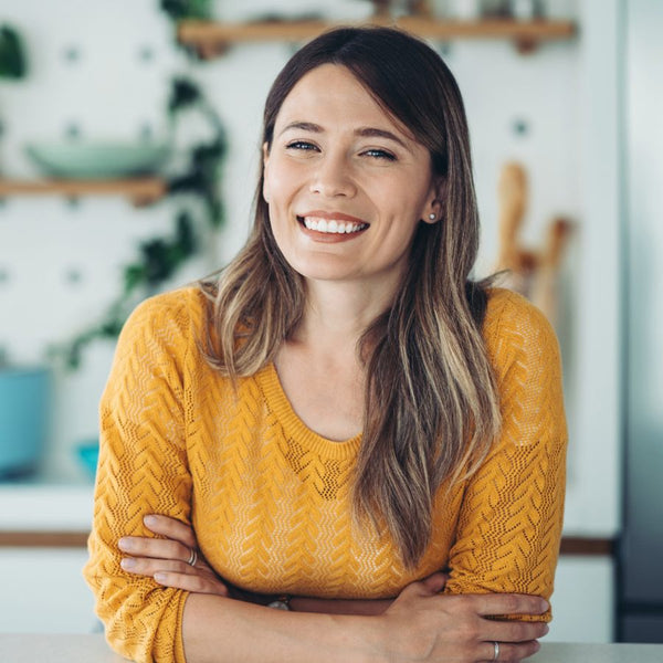Woman wearing a yellow sweater with a blurred indoor background